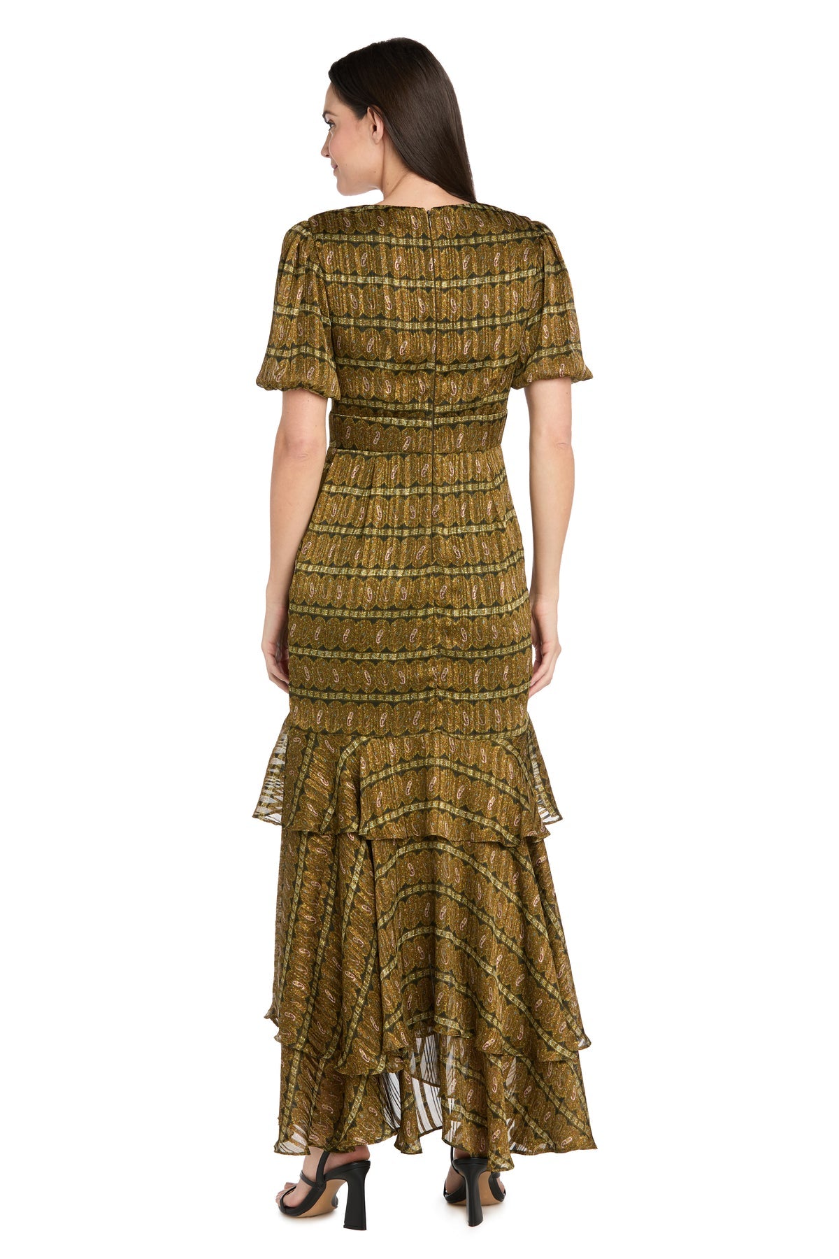 A woman stands with her back to the camera, wearing the R&M Richards 4157 Long Plaid Wedding Guest Dress in olive green—an ankle-length style with short sleeves and tiered ruffle hem—paired with black heeled sandals.